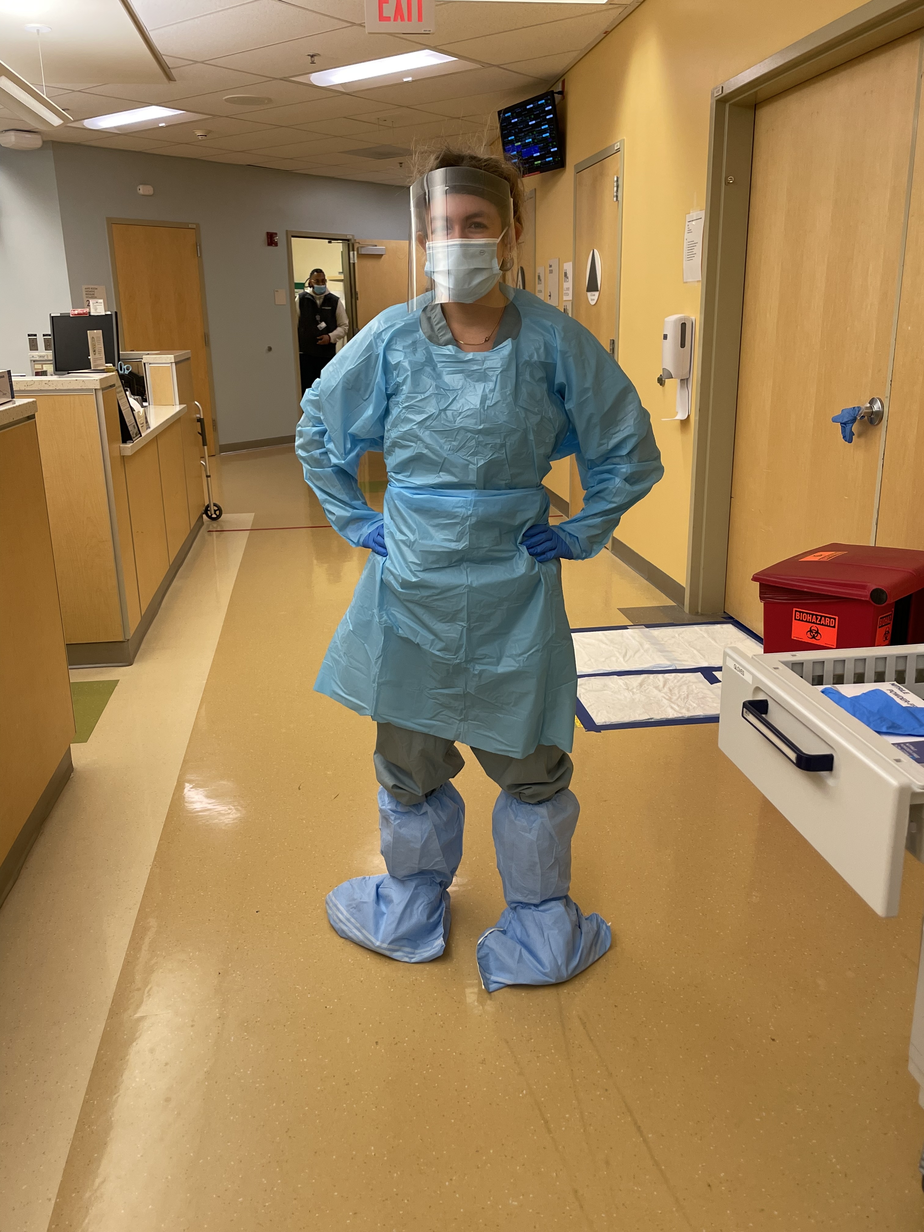 Jessi in full PPE — isolation gown, face shield, mask, gloves, and shoe covers — during her hospital nursing career